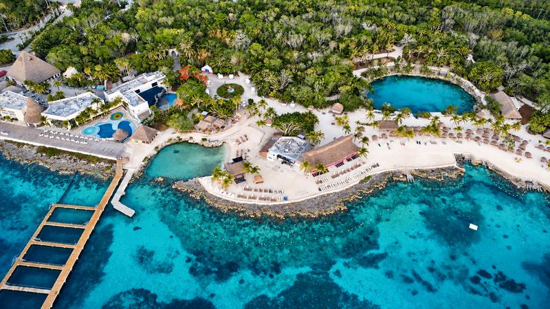 Aerial view of Chankanaab Park in Cozumel: the natural lagoon, white beach, palapas and the reef in turquoise water