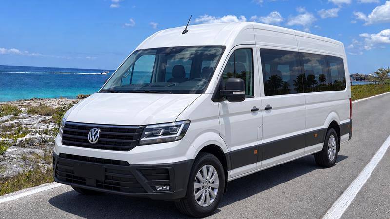 Private high-roof minibus for up to 19 guests on the coastal road in Cozumel, with the sea behind it